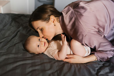 Mother kisses her baby on the bed
