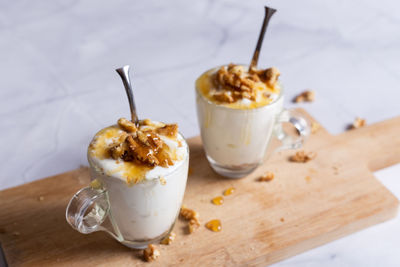 Cups of yogurt with honey and nuts on white background