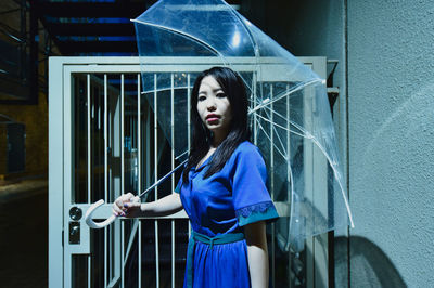 Young woman looking away while standing against blue wall