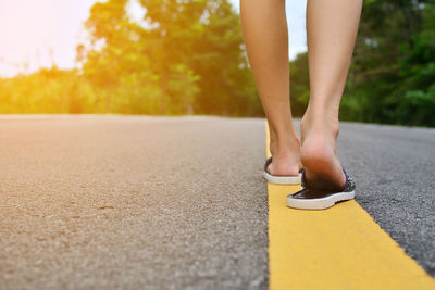 Low section of woman walking on road