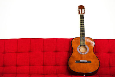 Guitar on sofa against wall against white background