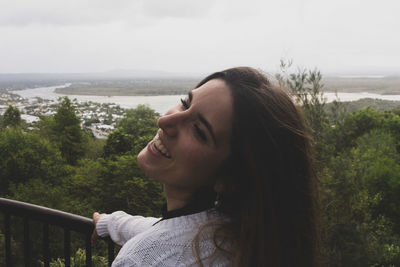 Portrait of beautiful woman by railing against sky