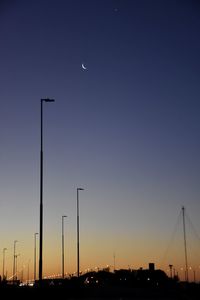 Silhouette street lights against clear sky at sunset