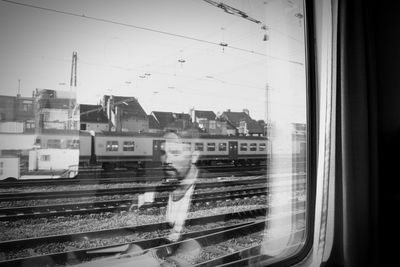 Train on railroad tracks against sky seen through window