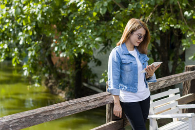 Portrait of young woman standing against railing