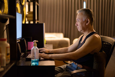 Side view of man sitting on table at home