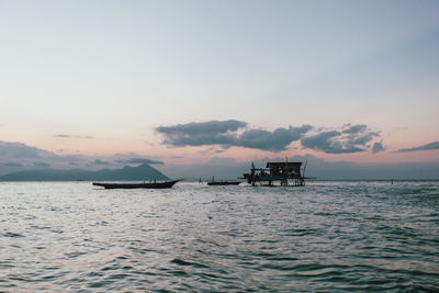 Silhouette boat in sea against sky during sunset