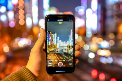 Close-up of hand using mobile phone in city