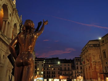 Low angle view of statue against illuminated buildings in city