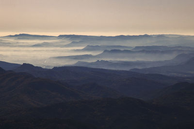 Mist over some layers of mountains in a landscape under a clear sky