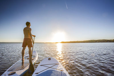 Man paddleboarding during sunset