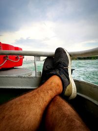 Low section of man on boat in sea against sky