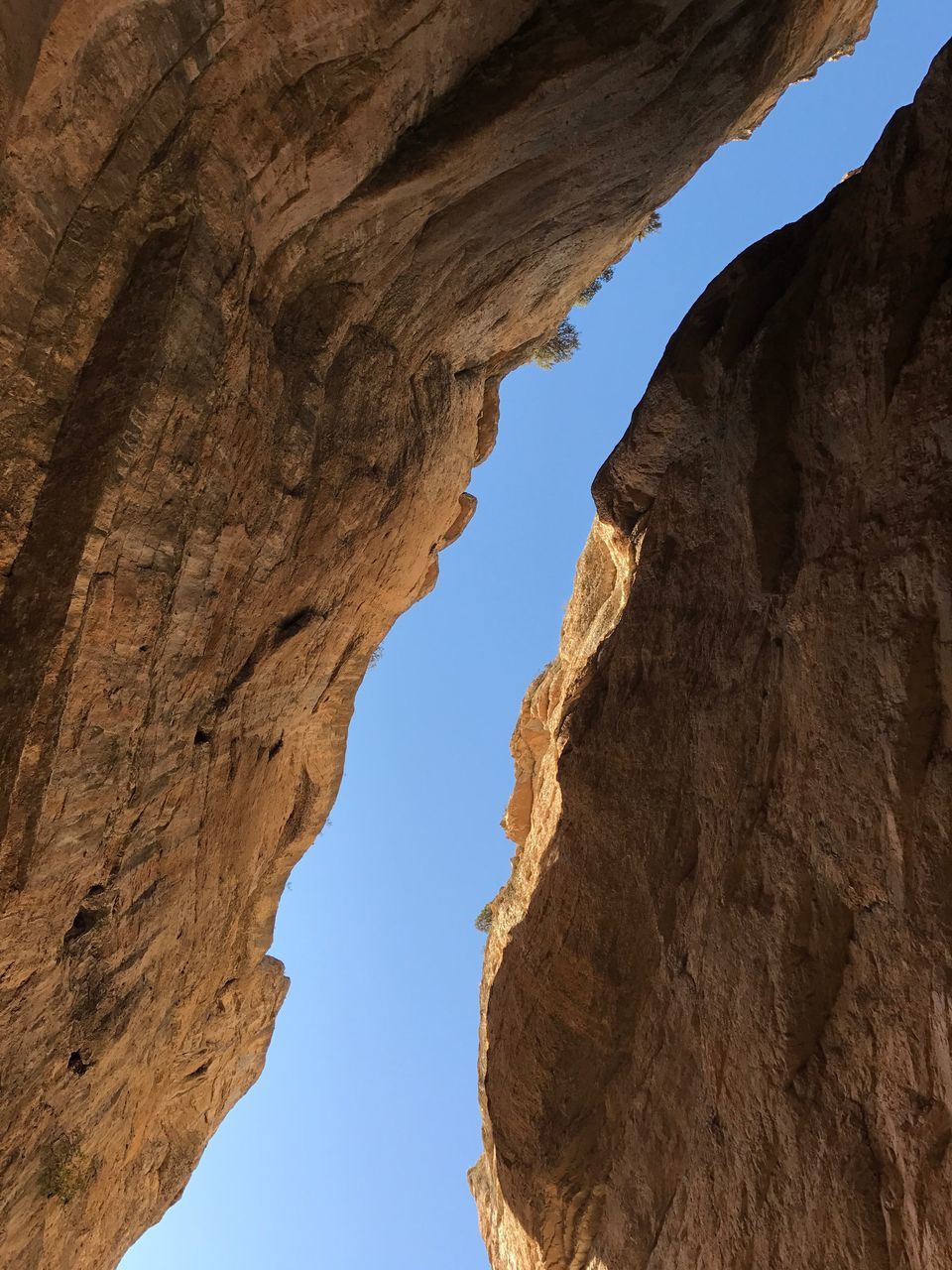 rock formation, geology, nature, physical geography, rock - object, natural arch, beauty in nature, tranquility, arch, day, travel destinations, arid climate, scenics, low angle view, tranquil scene, outdoors, no people, cliff, sunlight, textured, mountain, sky, clear sky