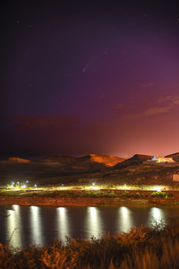 Scenic view of neowise comet over lake against sky at night