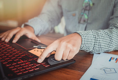 Midsection of man using mobile phone on table