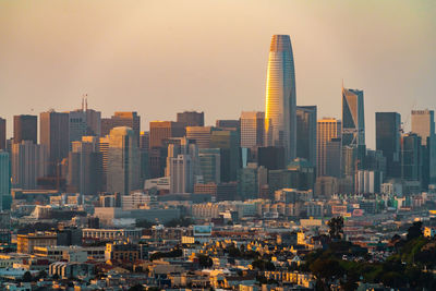 Modern buildings in city against sky during sunset