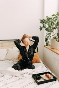 Young woman sitting on bed at home