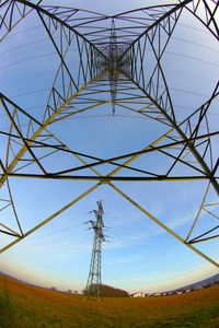 Low angle view of electricity pylon on field against sky