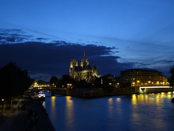 River in illuminated city against sky at night