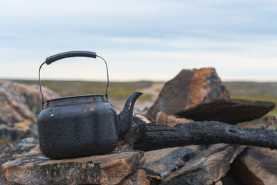 Teapot on stone against sky