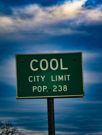 Low angle view of sign board against cloudy sky