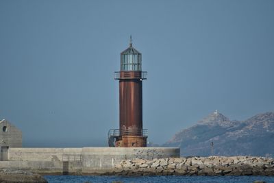 Lighthouse by sea against sky