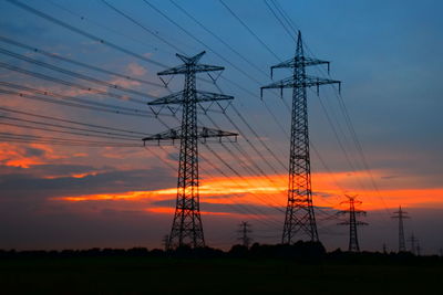 Low angle view of electricity pylon against sky during sunset