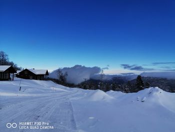 Snow covered landscape against blue sky