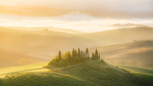 Italy, tuscany - podere belvedere farmhouse at sunrise with view of val d'orcia hills.