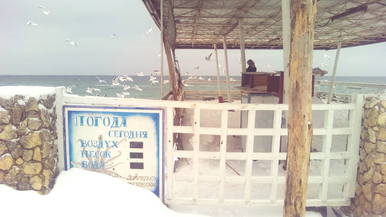 sea, text, water, communication, western script, built structure, architecture, building exterior, horizon over water, guidance, day, sky, beach, outdoors, information sign, window, incidental people, sign, rear view