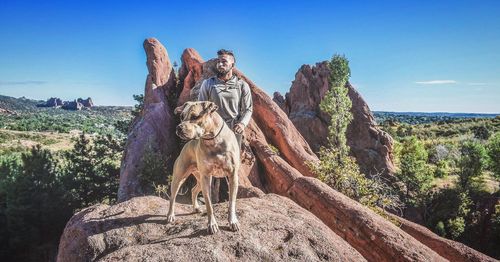 Man with dog standing at red rock canyon national conservation area against sky