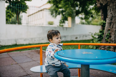 Cute boy sitting at bench at park