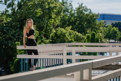 Thoughtful young woman standing on balcony against trees