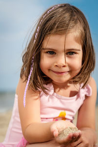 Portrait of smiling girl holding sand at beach