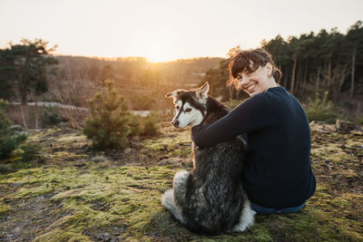 Woman with dog on field during sunset