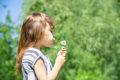 Cute girl blowing dandelion seed