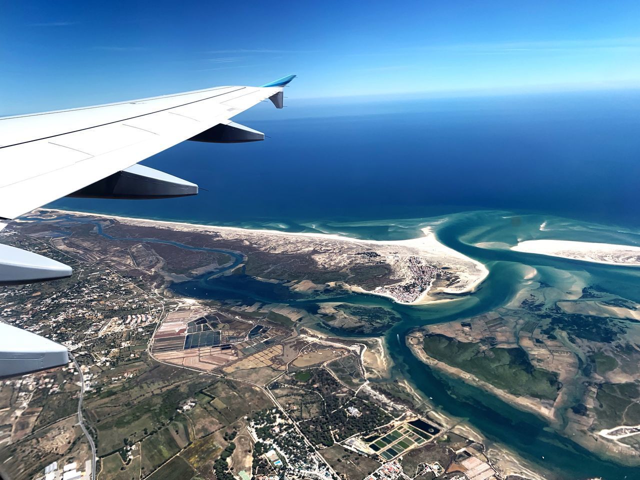 AERIAL VIEW OF SEA AND AIRPLANE WING AGAINST SKY