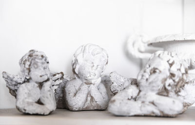 Close-up of angel figurines on table against wall