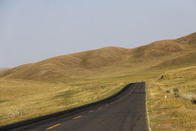 A flat newly built asphalt road leads to the foot of the mountain on the golden prairie