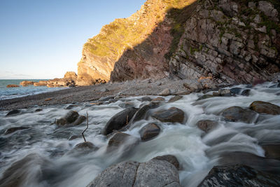 Rock formations by sea against sky