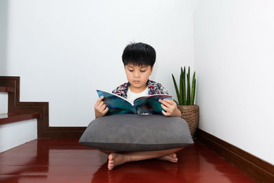 Portrait of boy sitting on chair at home