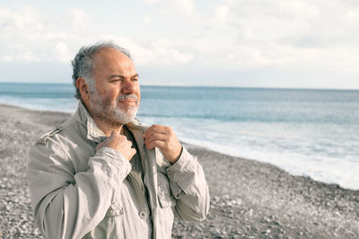 Happy middle-aged bearded man walking along deserted winter beach. concept of leisure activities