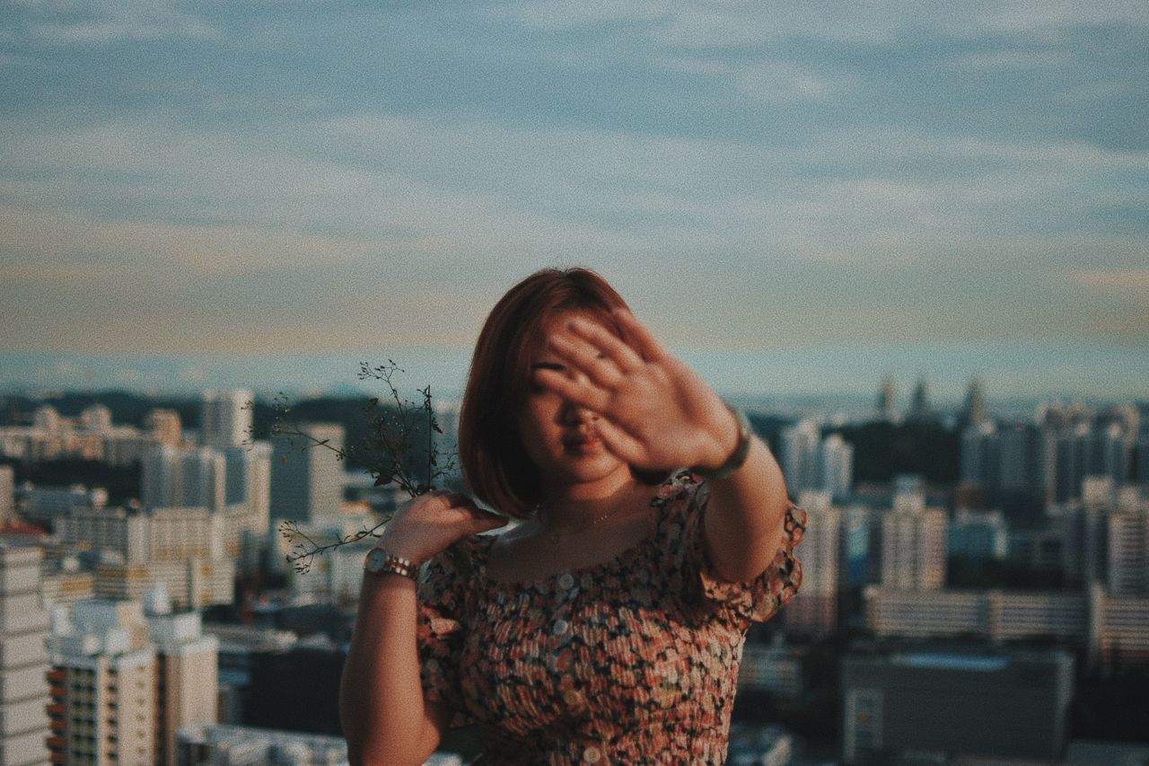 PORTRAIT OF WOMAN WITH CITYSCAPE IN BACKGROUND