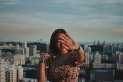 Portrait of woman in city against sky