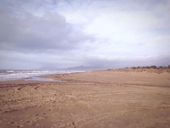 Scenic view of beach against cloudy sky