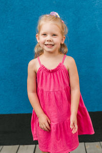 Portrait of girl standing against blue wall