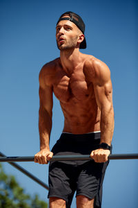 Low angle view of shirtless man standing against clear sky