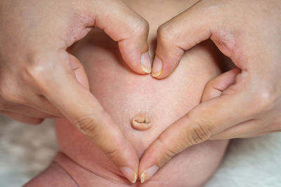 Close-up of woman hand by baby stomach