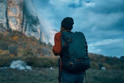 Rear view of man standing on mountain against sky