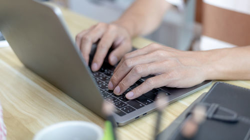 Midsection of woman using laptop at table